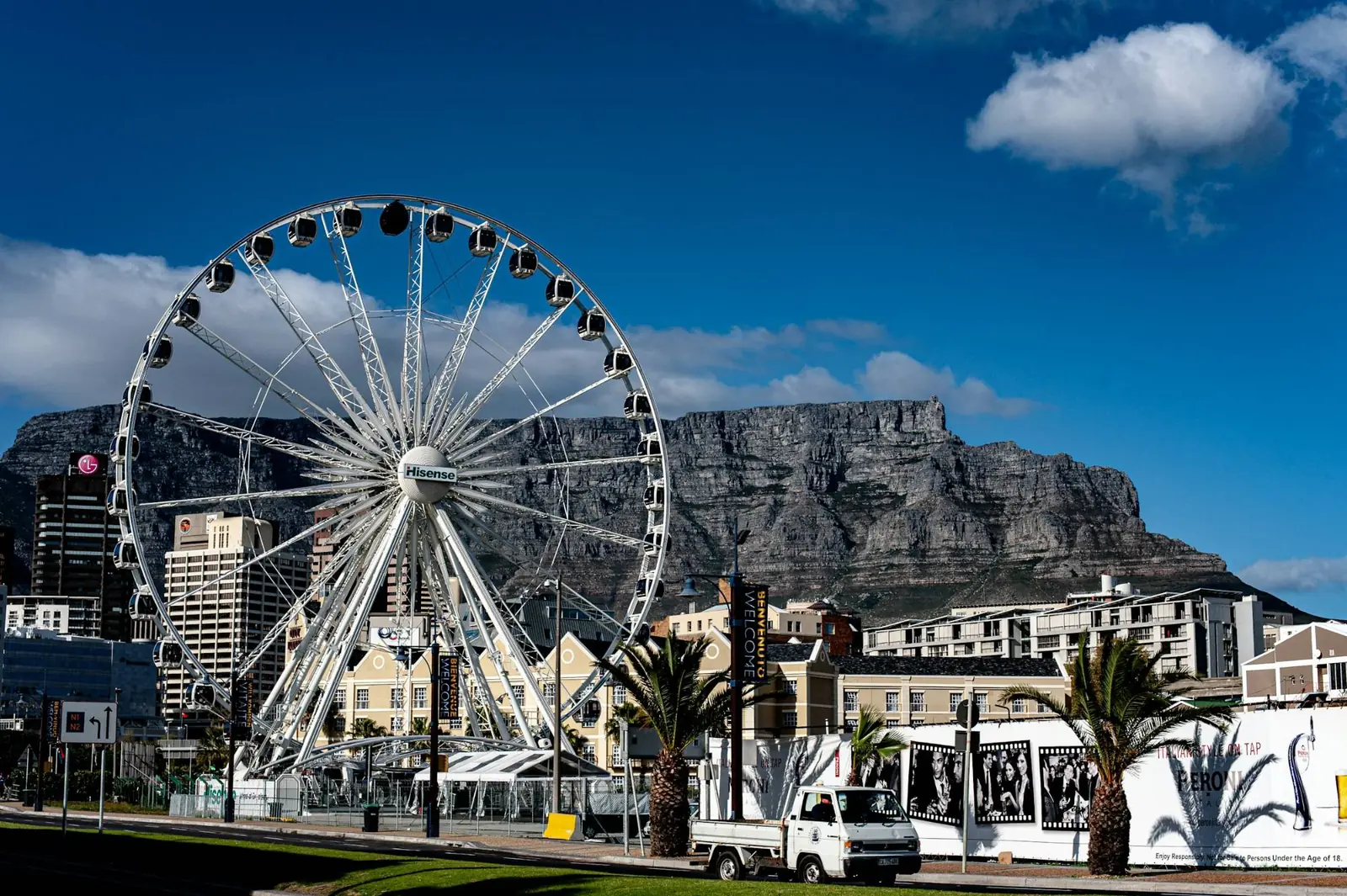 The Cape Wheel at the V&A Waterfront in Cape Town, with Table Mountain behind it under a clear blue summer sky.